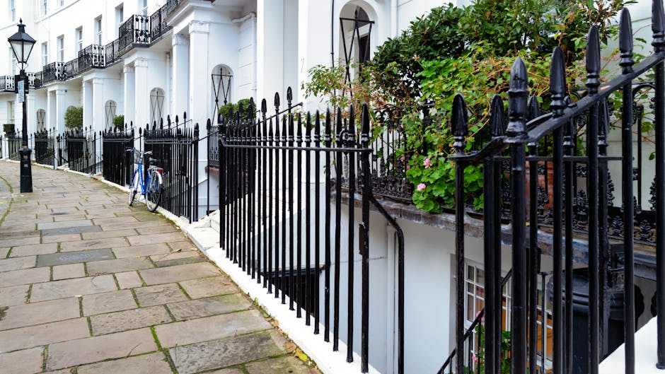 A narrow residential street in West Kensington, lined with parked cars on both sides, including several small hatchbacks and sedans. The street is bordered by Victorian-style terraced houses with whit