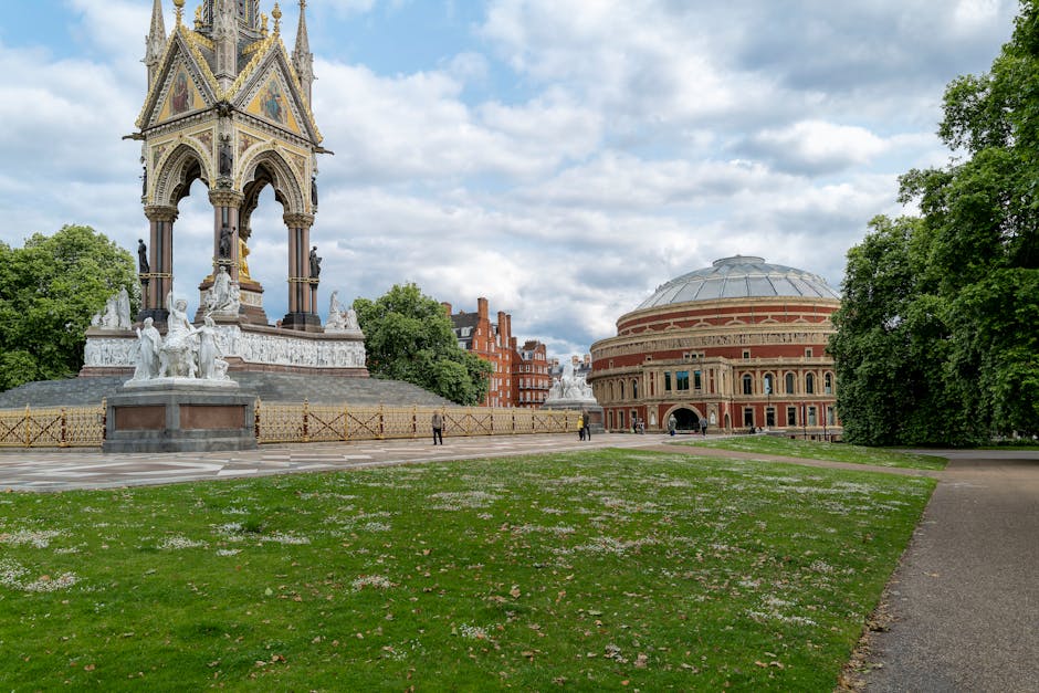 A large historic building with intricate architectural details, featuring a prominent central tower topped with decorative spires, situated on a street in South Kensington. The façade is made of ligh