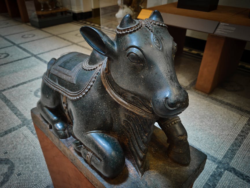 A detailed photograph of a black, antique-style bronze or metal sculpture of a boar, mounted on a rectangular wooden base. The boar features intricate decorative elements, including a saddle with engr